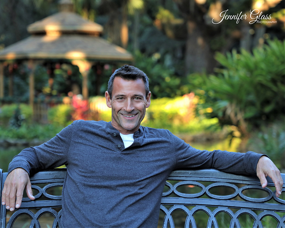 man smiling sitting on bench in beautiful park photo